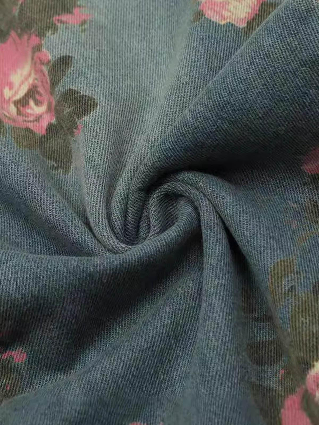 Intricate fabric detail of TALISHKO floral print jeans, highlighting pink roses on denim.