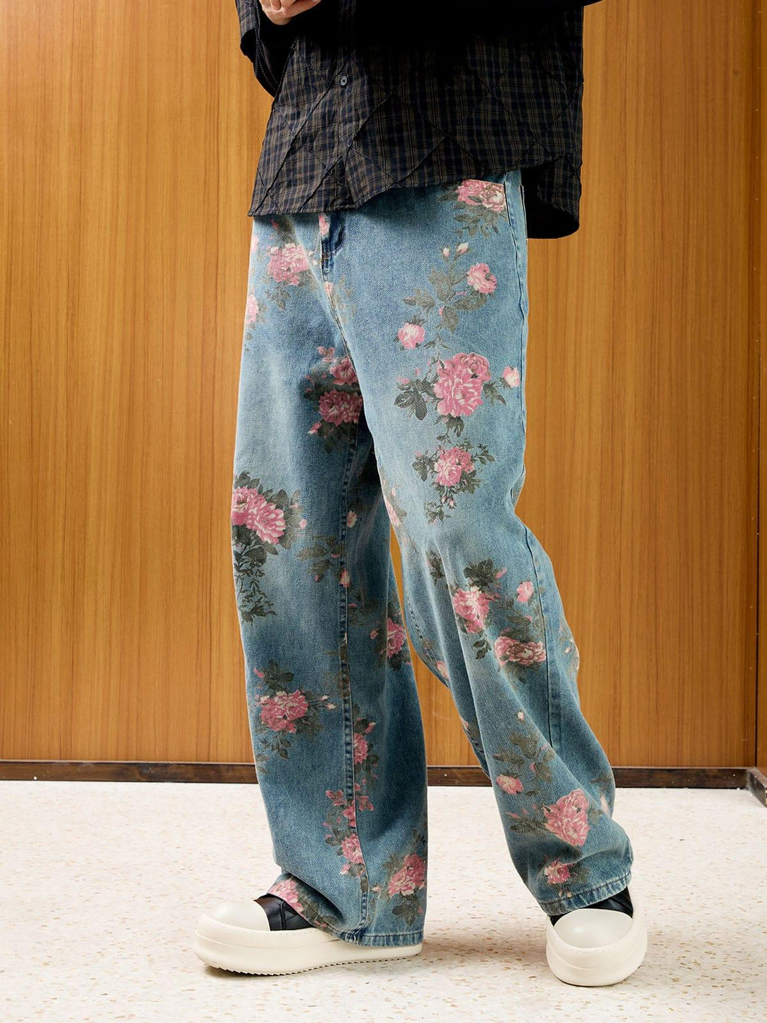 Model in floral print jeans by TALISHKO, paired with a plaid shirt, highlighting casual style.
