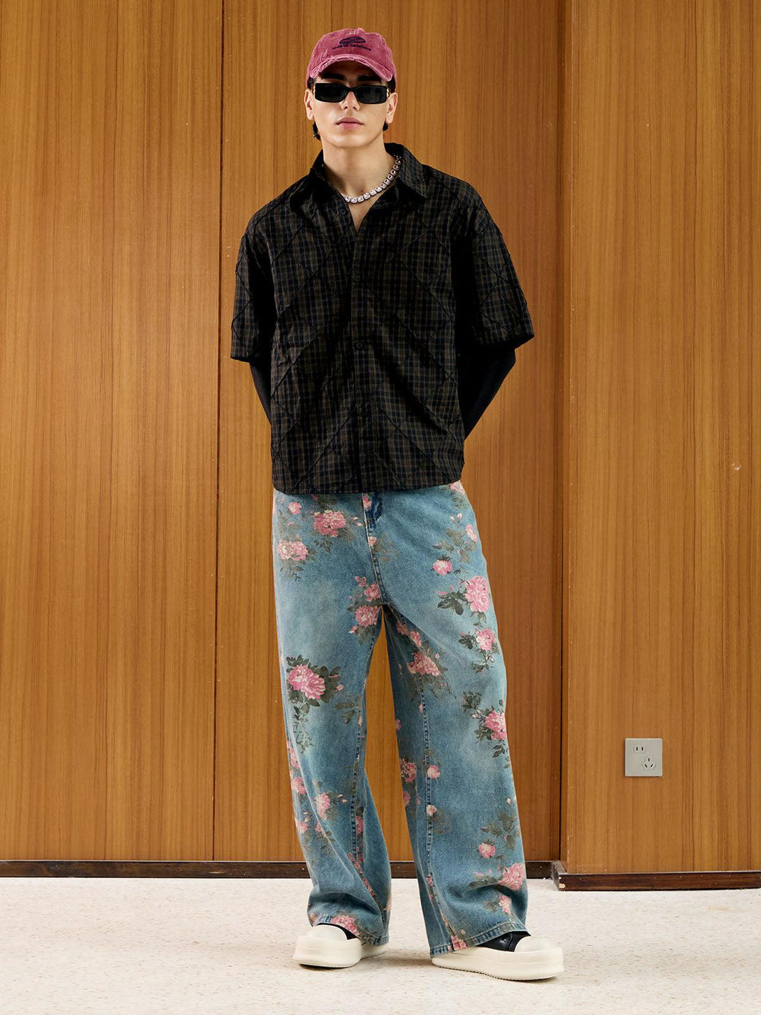 Model wearing floral print straight jeans by TALISHKO, paired with a plaid shirt and cap.
