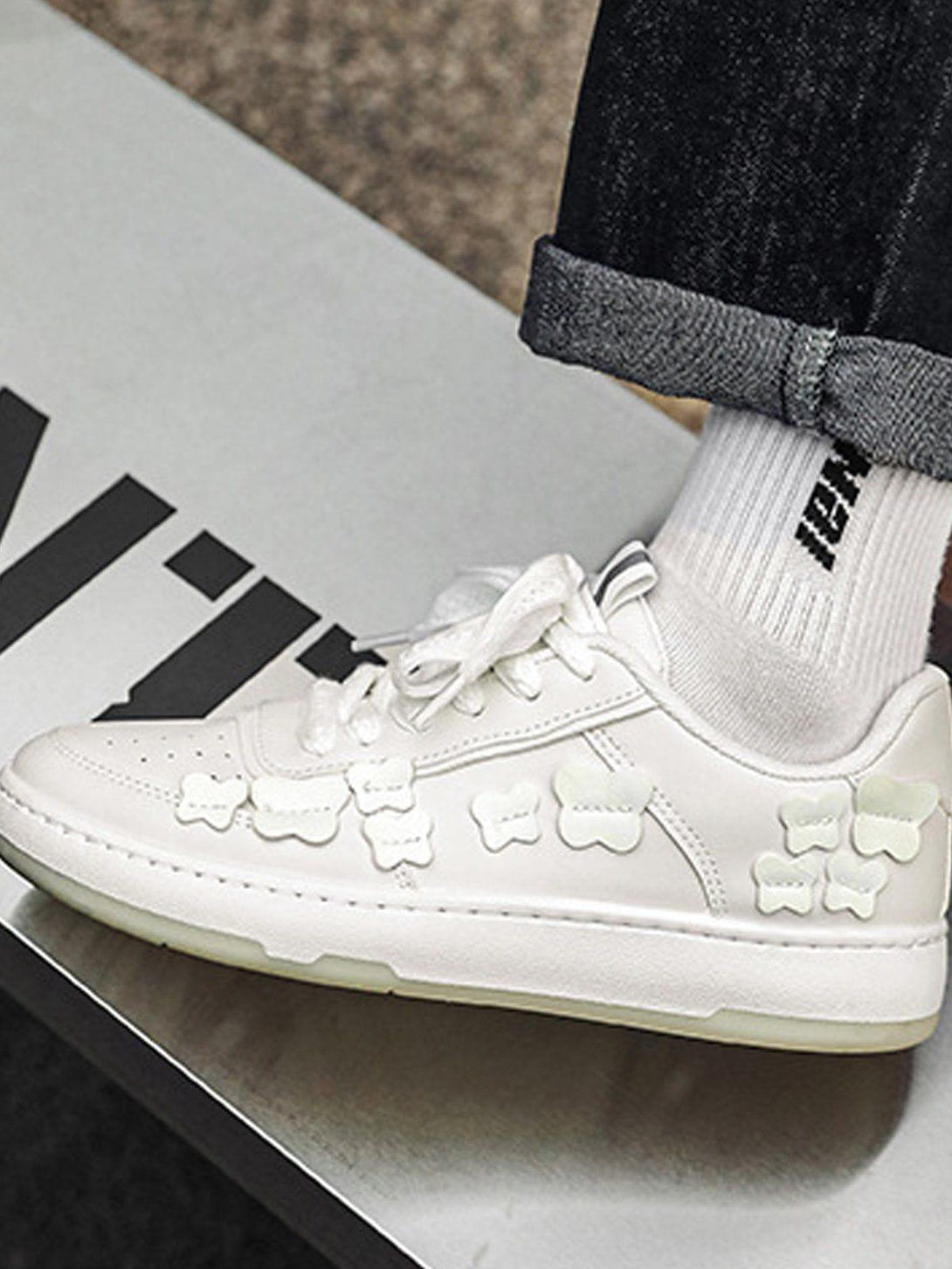 White skate shoes with fluorescent butterfly details by TALISHKO, paired with cuffed jeans.