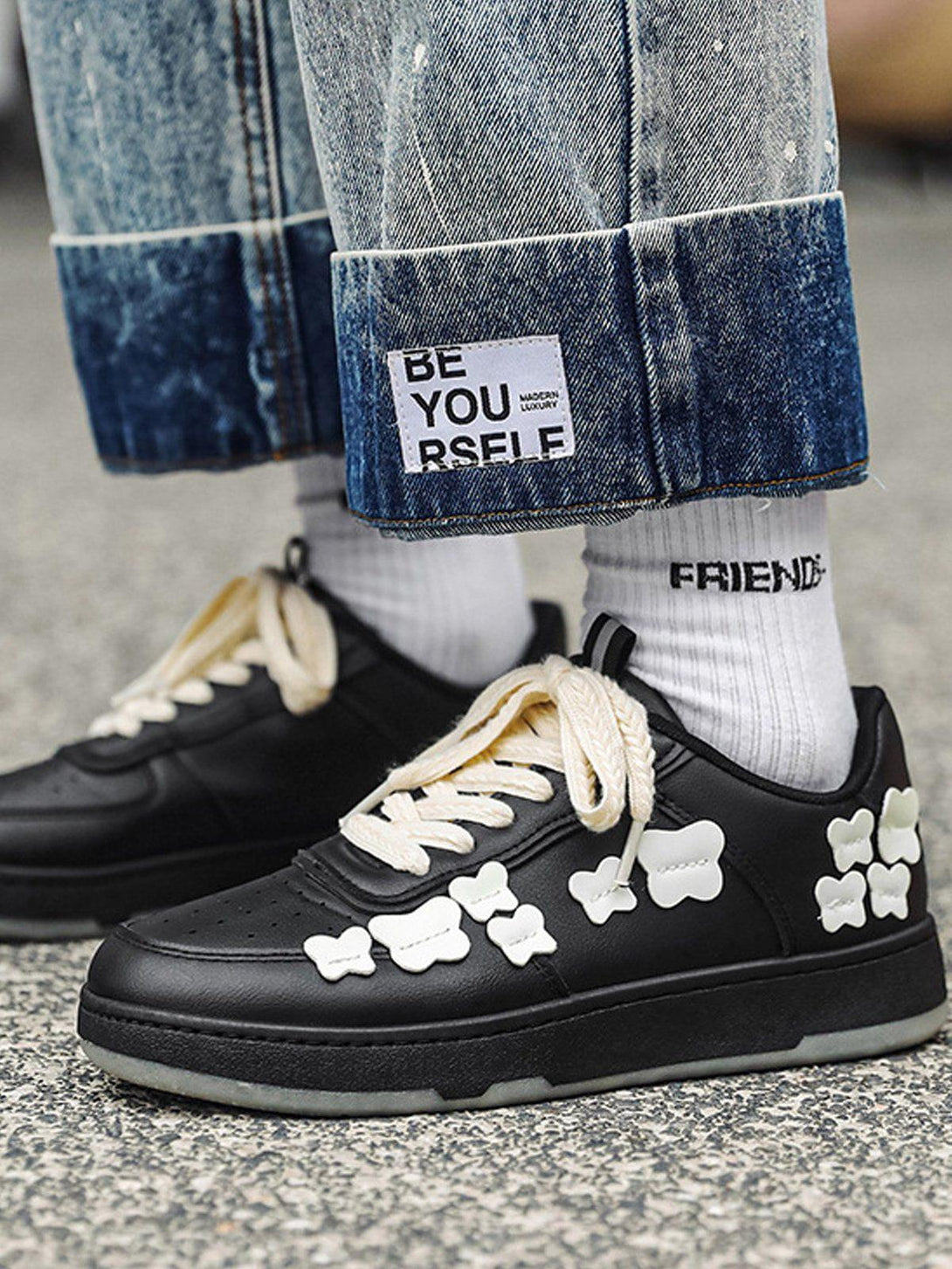 Black skate shoes with white butterfly details worn with cuffed jeans, by TALISHKO, adding a unique touch to streetwear.