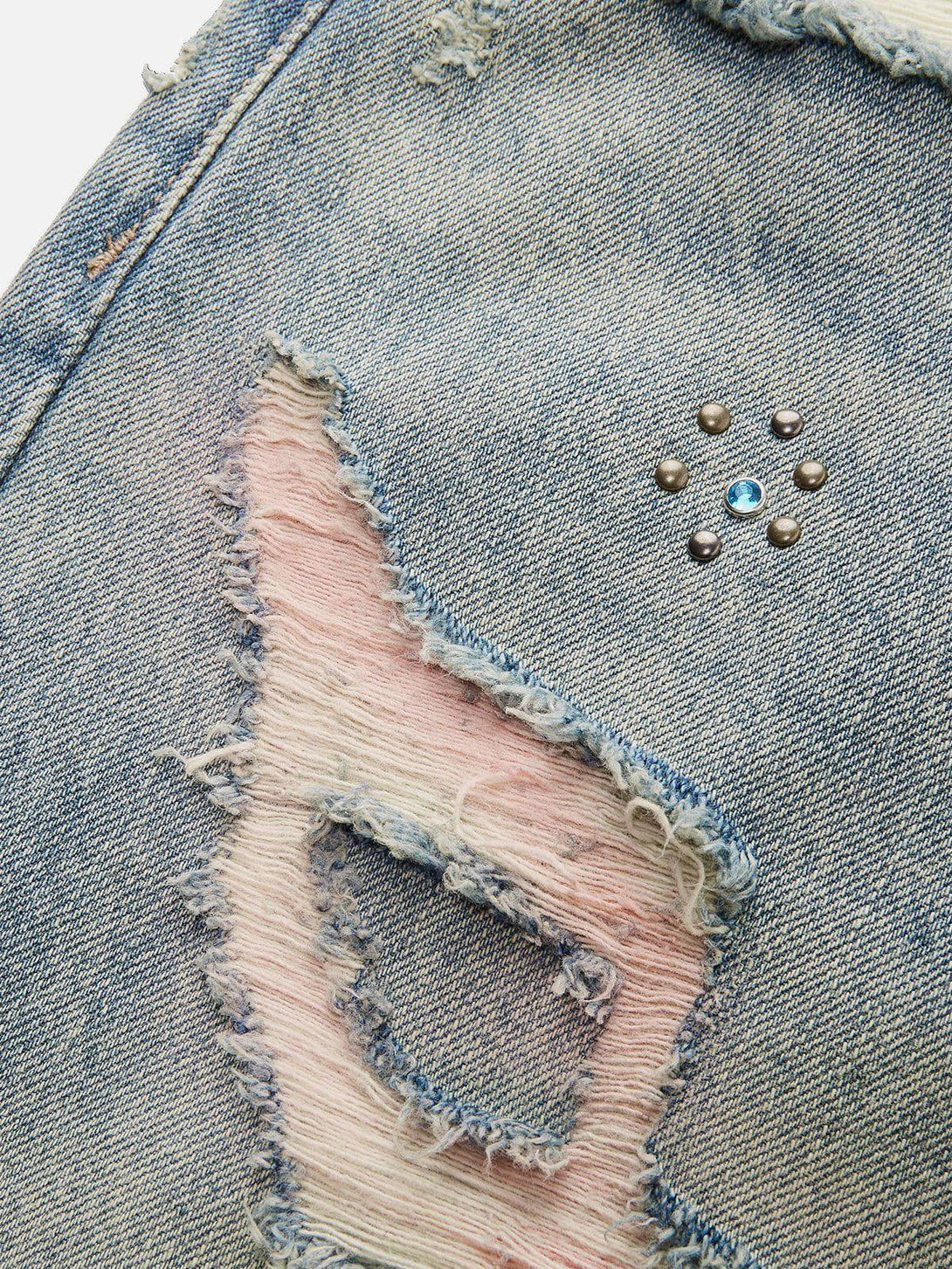A detailed view of TALISHKO fringe distressed jeans, highlighting intricate denim texture.