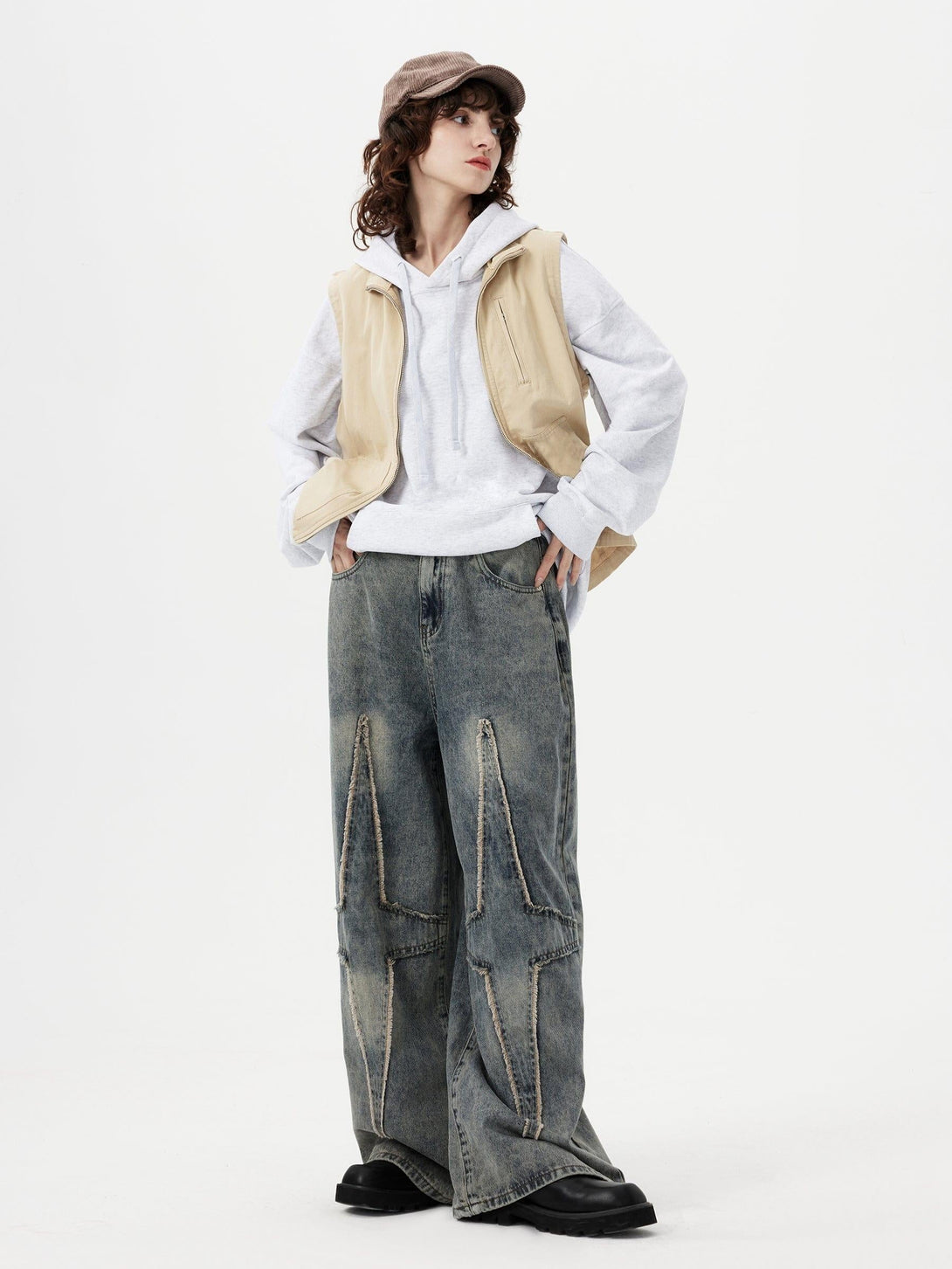 Model styled in TALISHKO fringe star jeans, paired with a casual hoodie and beige vest.