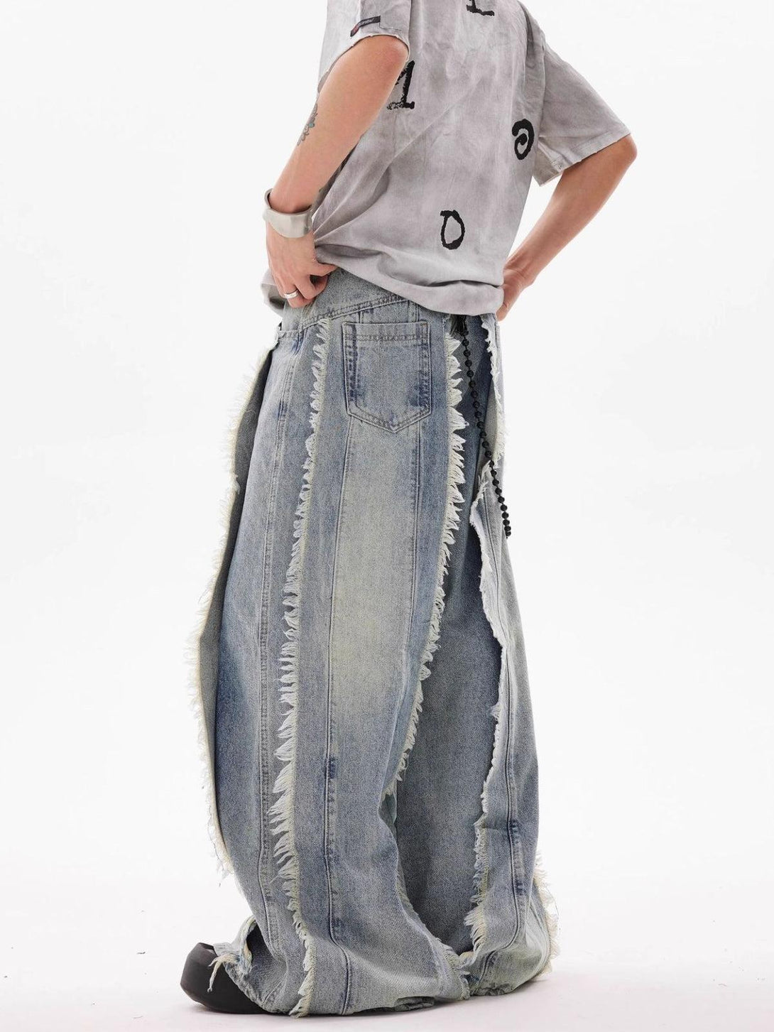 Side view of TALISHKO fringe washed jeans, highlighting the wide-leg style and frayed edges.