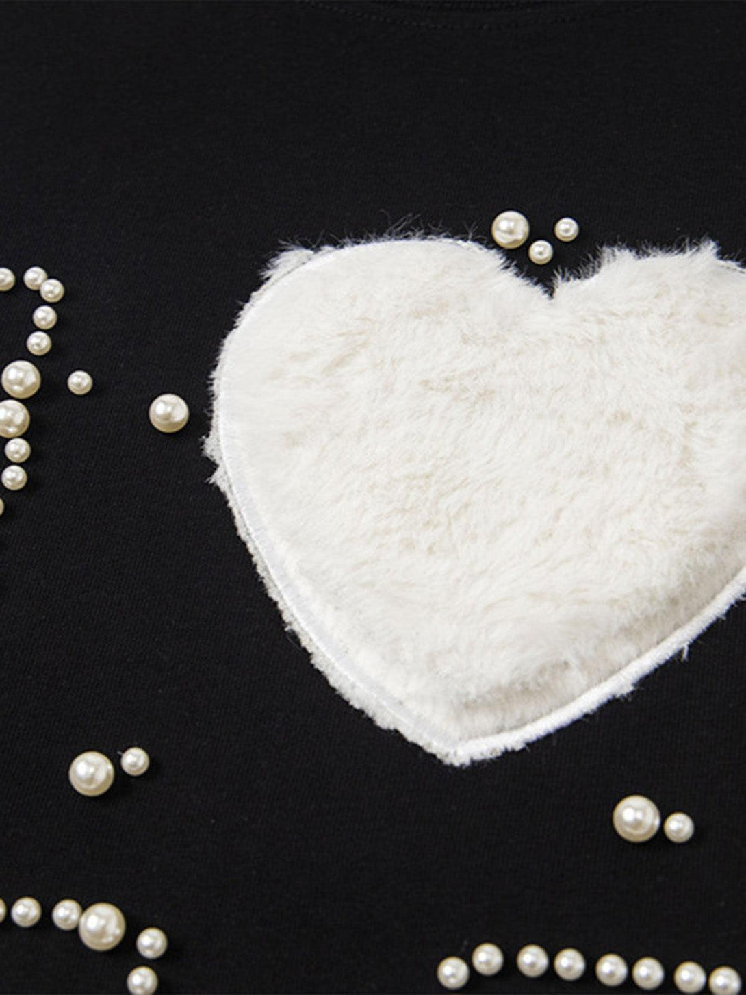 Focusing on the textured heart and pearl embellishments of the "Love Me" T-shirt by TALISHKO.