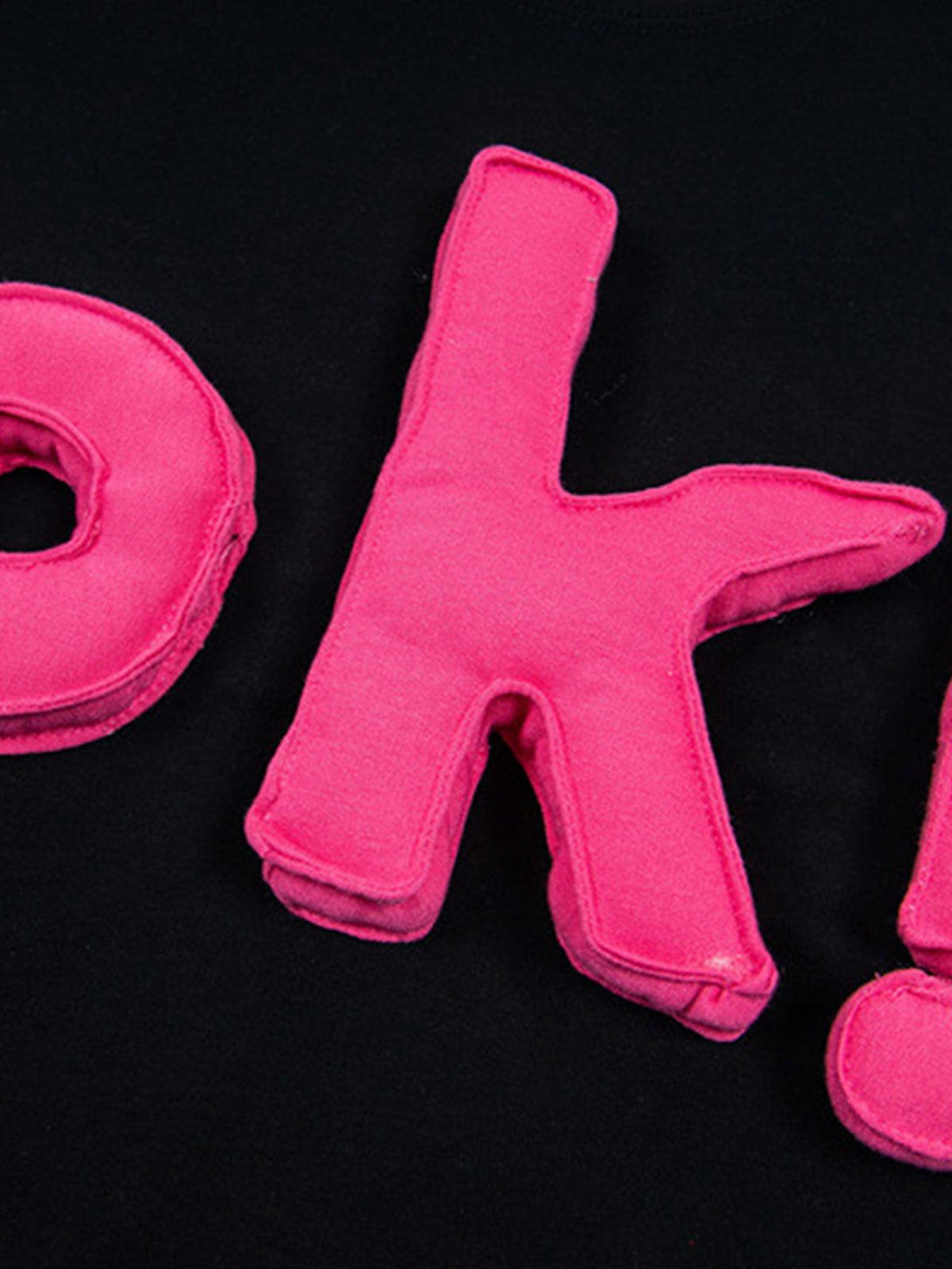 Focusing on the vibrant pink "OK!" design on a black T-shirt, crafted by TALISHKO.