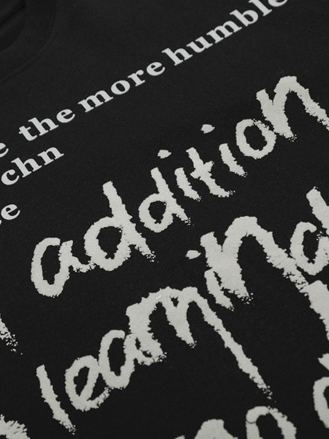 A tight crop highlighting the artistic letter print on a black T-shirt by TALISHKO.