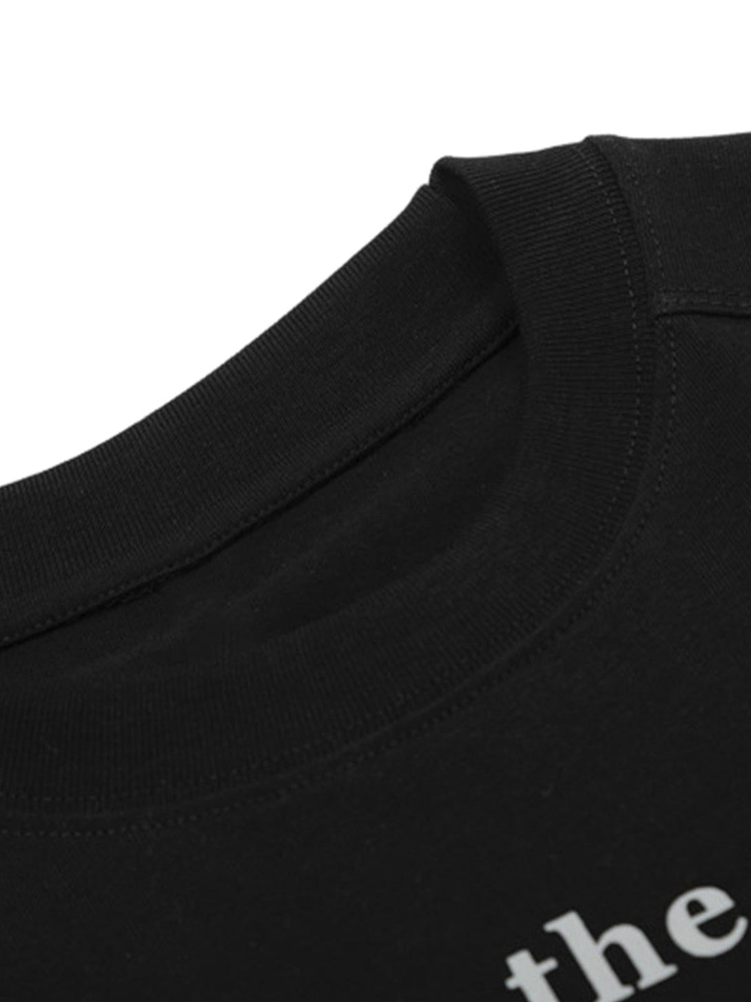 Detailed fabric and stitching on a black letter print T-shirt by TALISHKO, highlighting quality.