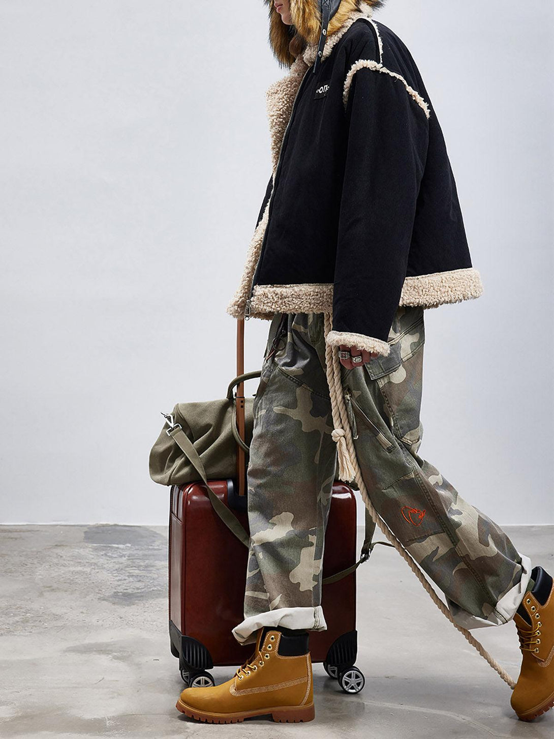 TALISHKO sherpa-lined jacket with fur collar, paired with camo pants and boots for a rugged look.