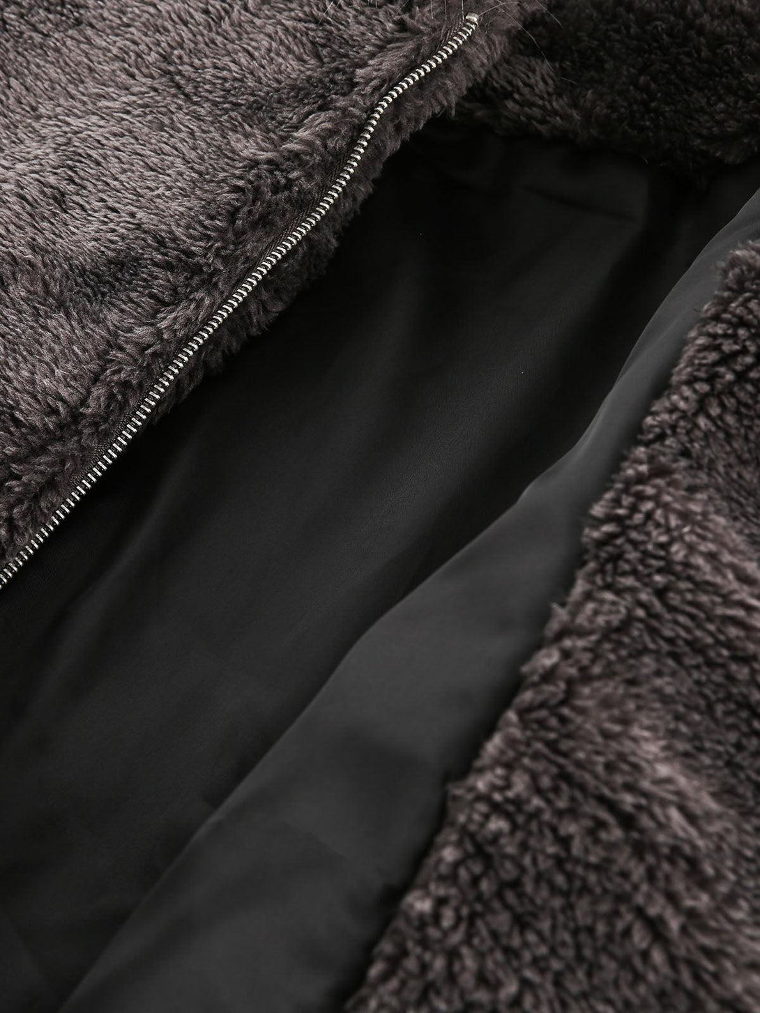 A tight crop highlighting the plush interior of TALISHKO's sherpa jacket with a zipper detail.