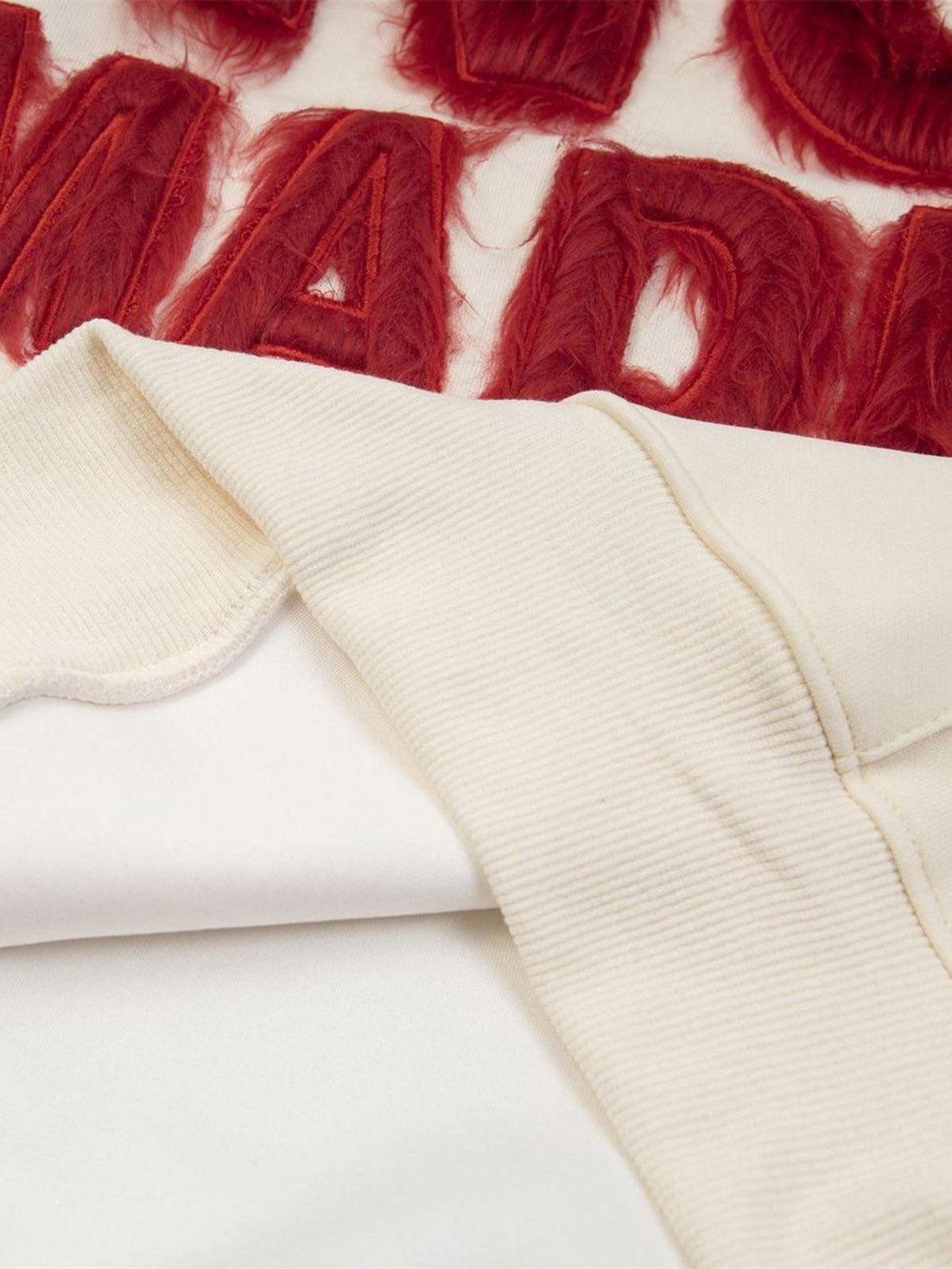 A detailed view of red fur patchwork embroidery on a hoodie by TALISHKO, highlighting texture.