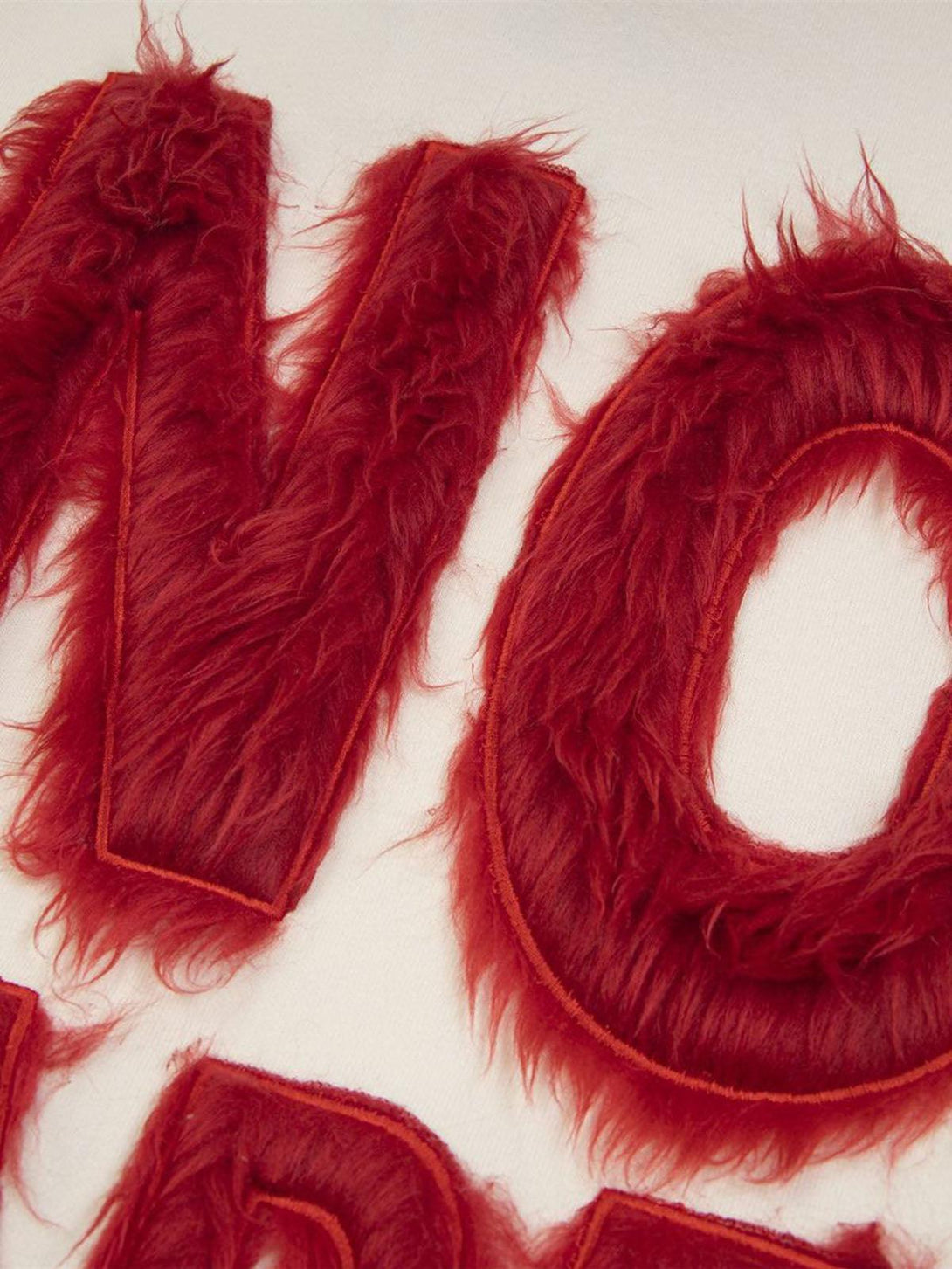 Zoomed-in texture of a red fur patchwork with embroidery on a hoodie by TALISHKO.
