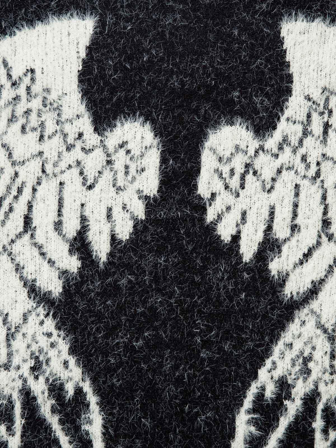 Zoomed-in texture of TALISHKO's fuzzy sweater, highlighting intricate wing patterns in black and white.