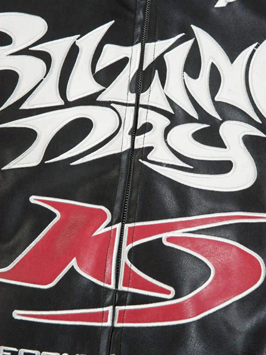 Intricate look at TALISHKO's jacket, highlighting bold graphic lettering on a black fabric.