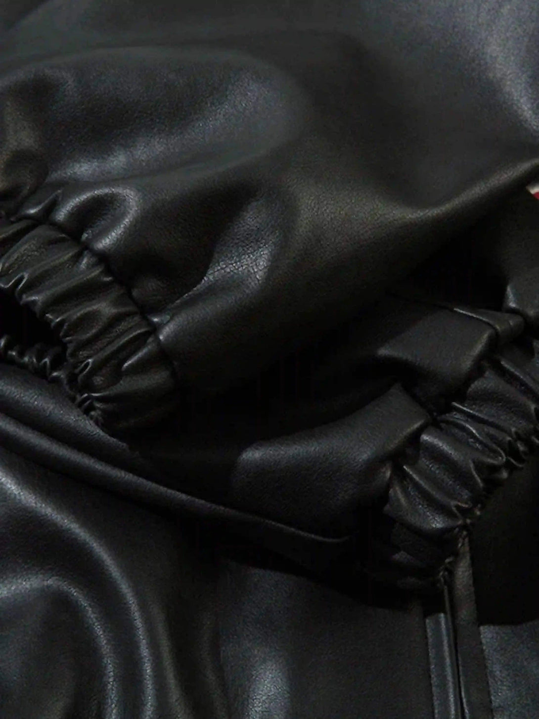 Zoomed-in texture of TALISHKO jacket's black fabric, highlighting the elastic detailing.