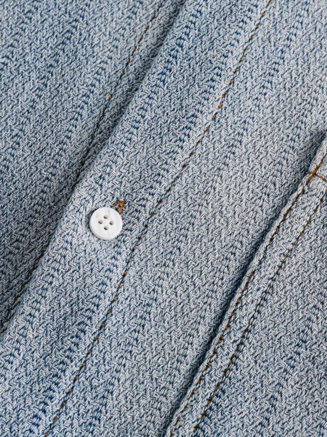 Detailed fabric and stitching of TALISHKO's gradient denim shirt, highlighting texture and button.
