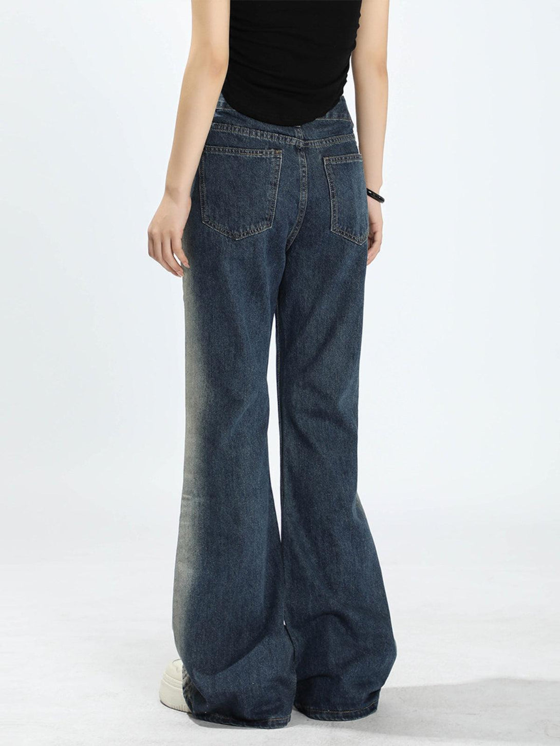 Model showcasing the back view of TALISHKO's gradient patchwork jeans with a flared cut.