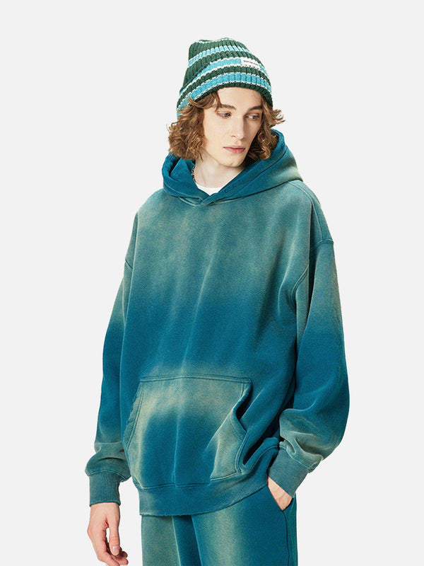 Model wearing a gradient washed hoodie by TALISHKO, paired with a striped beanie for a cozy look.