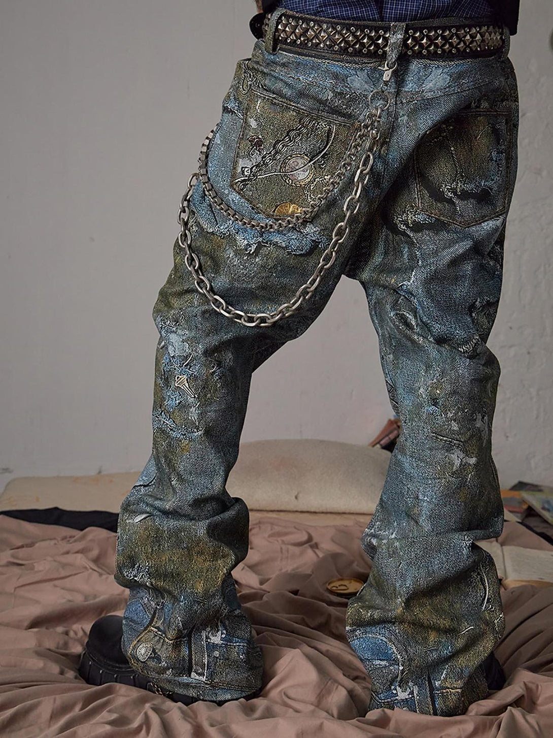 Back view of TALISHKO jeans featuring graffiti design and chain accents on a textured fabric.