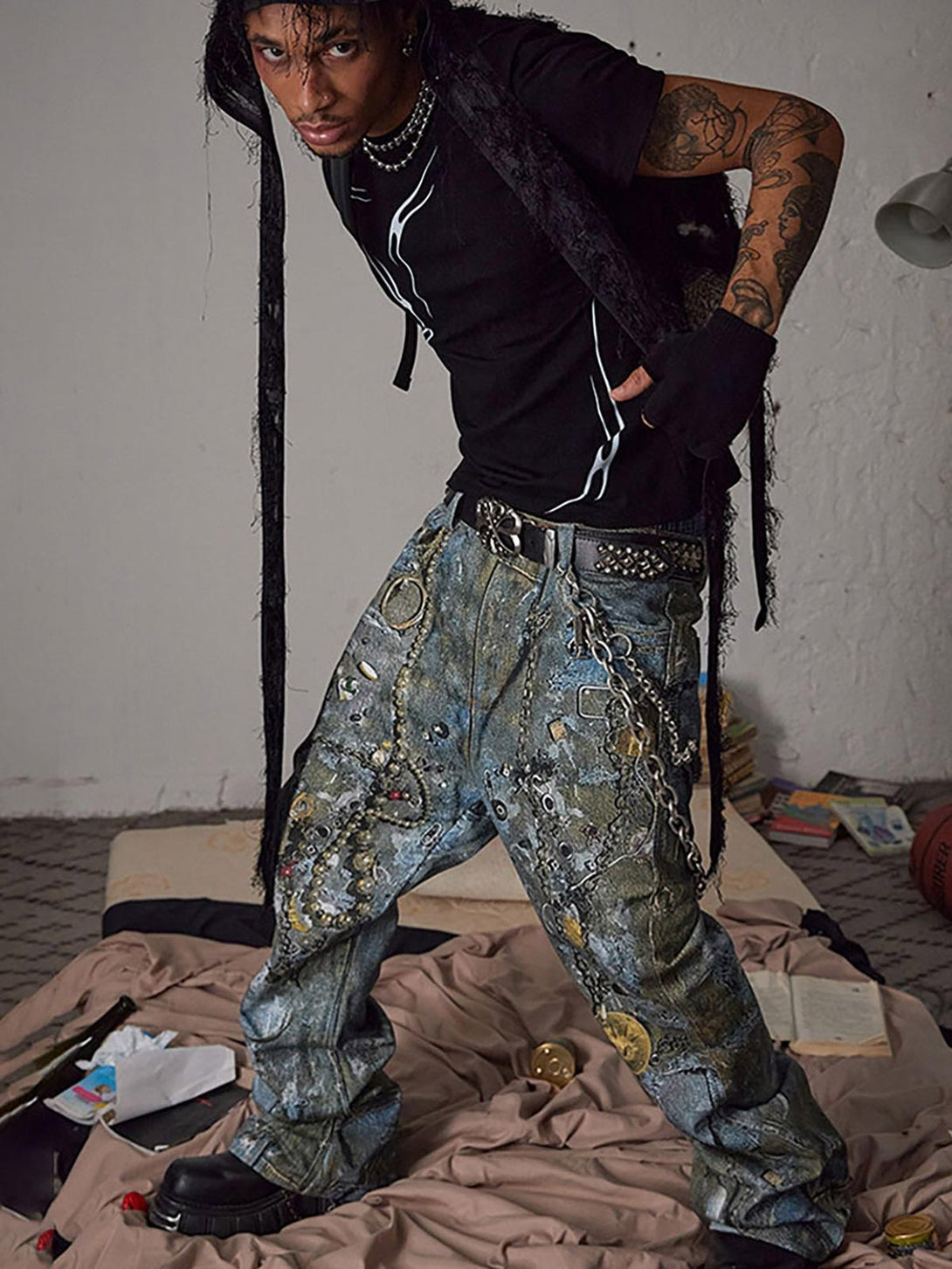Model showcasing TALISHKO jeans with graffiti design and chains, styled with a black tee.