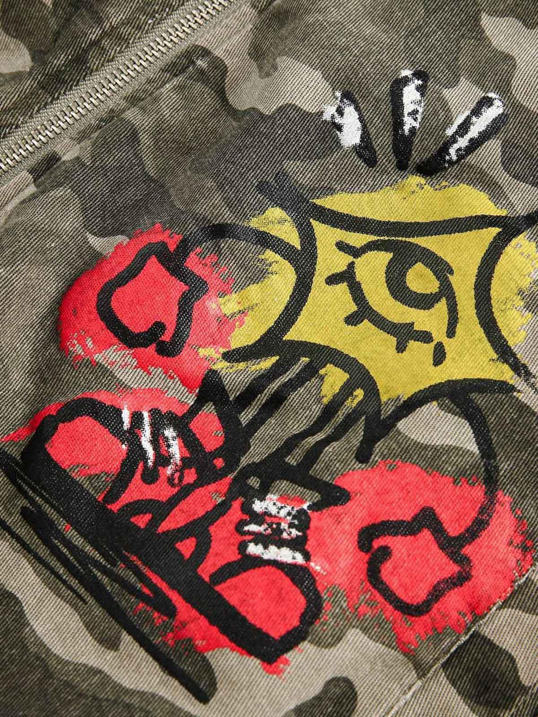 Intricate look at graffiti artwork on a TALISHKO camouflage bomber jacket, highlighting urban style.