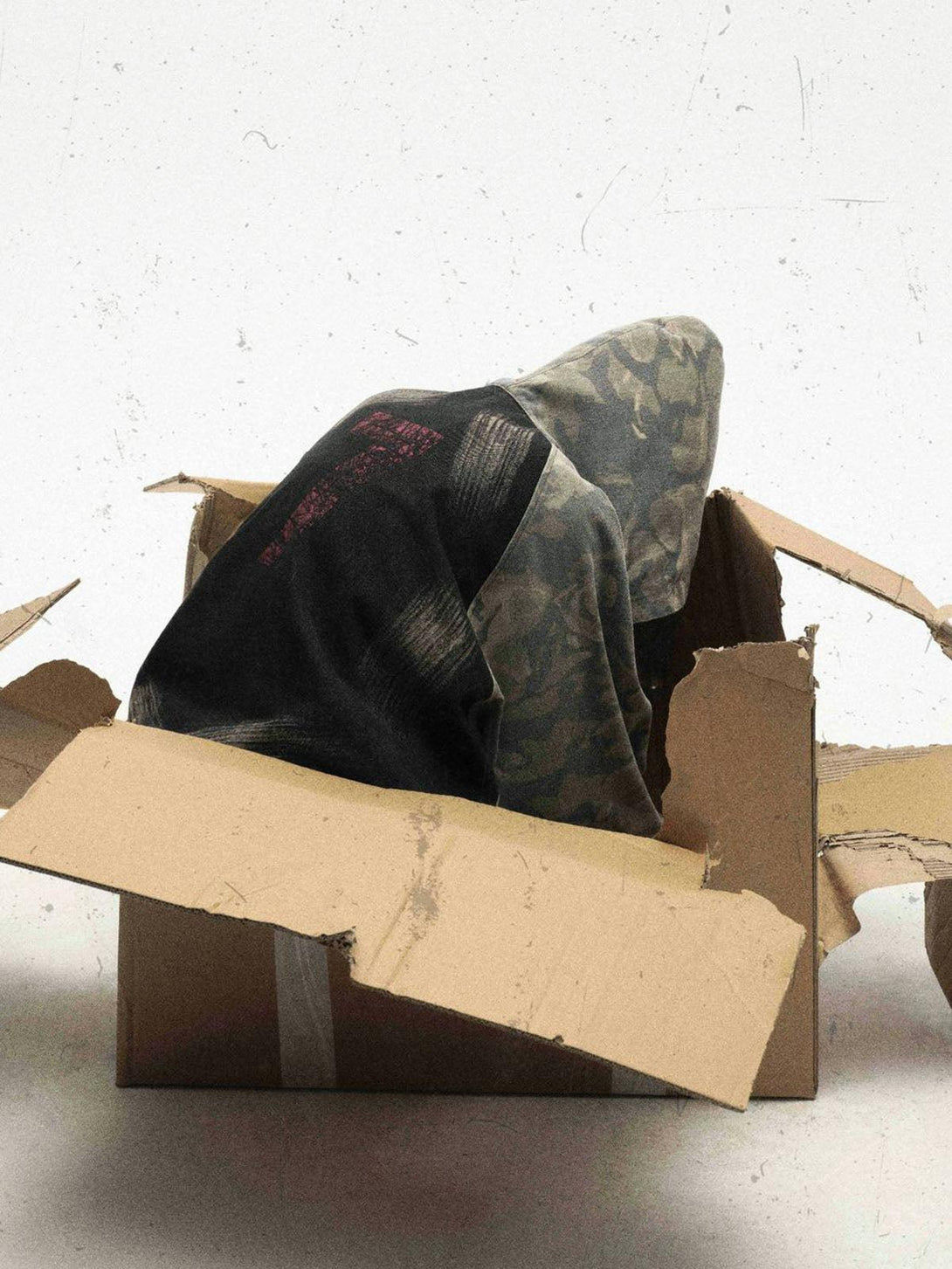 TALISHKO's graffiti camouflage hooded jacket creatively displayed in an open cardboard box.