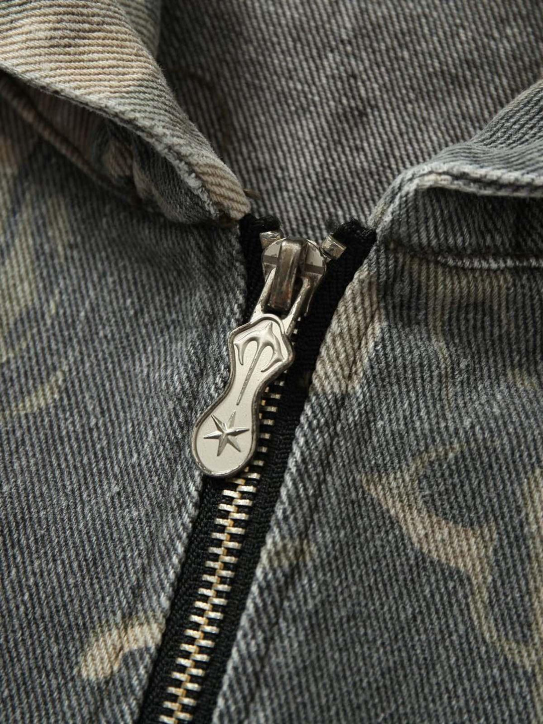 Intricate look at the zipper detail on TALISHKO's graffiti camouflage patchwork hooded jacket.