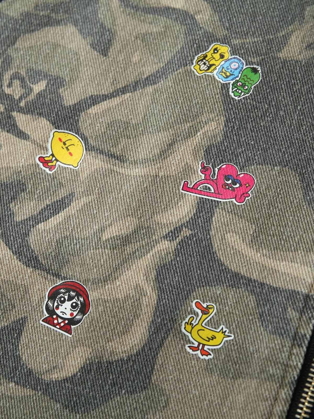 Playful sticker details on TALISHKO's graffiti camouflage jacket, adding quirky charm.