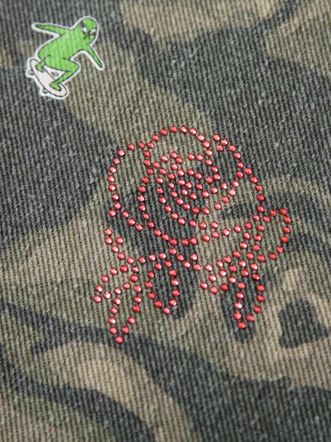 Detailed fabric and patchwork design on TALISHKO's graffiti camouflage jacket, highlighting unique embellishments.