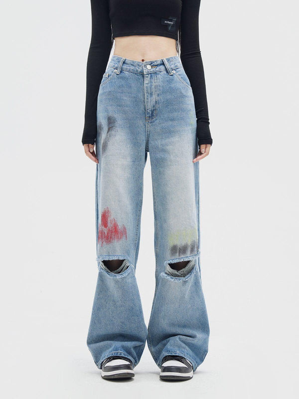 Model wearing graffiti distressed jeans by TALISHKO, featuring knee rips and artistic accents.