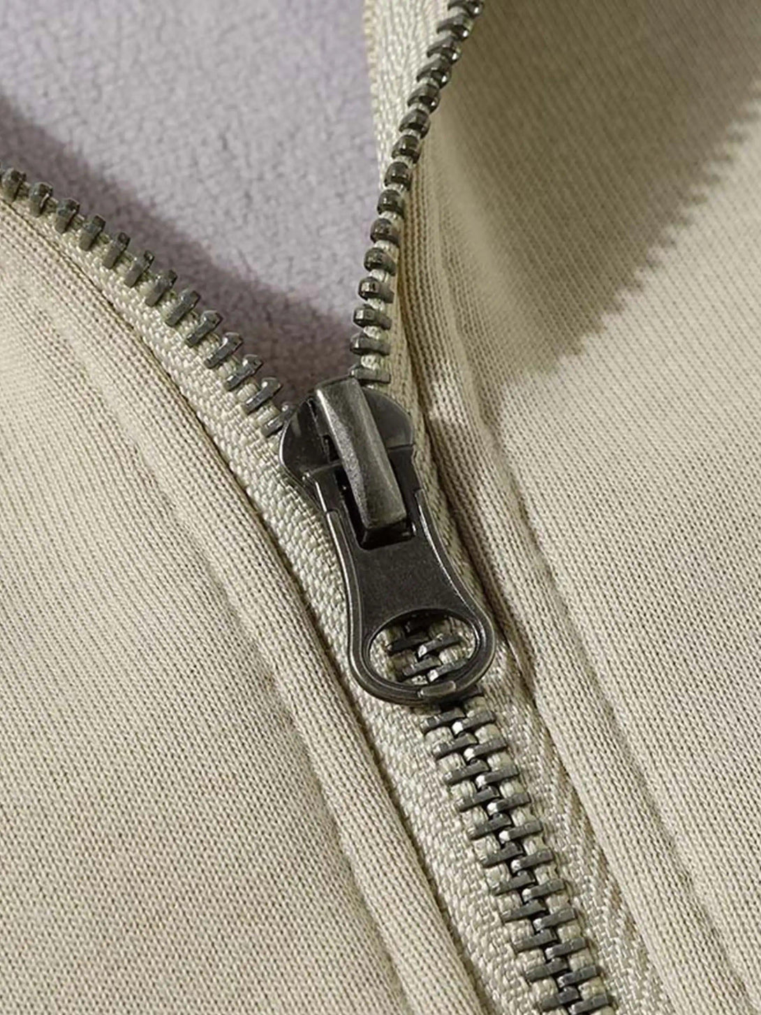 A tight crop highlighting TALISHKO's jacket zipper, emphasizing quality and craftsmanship.