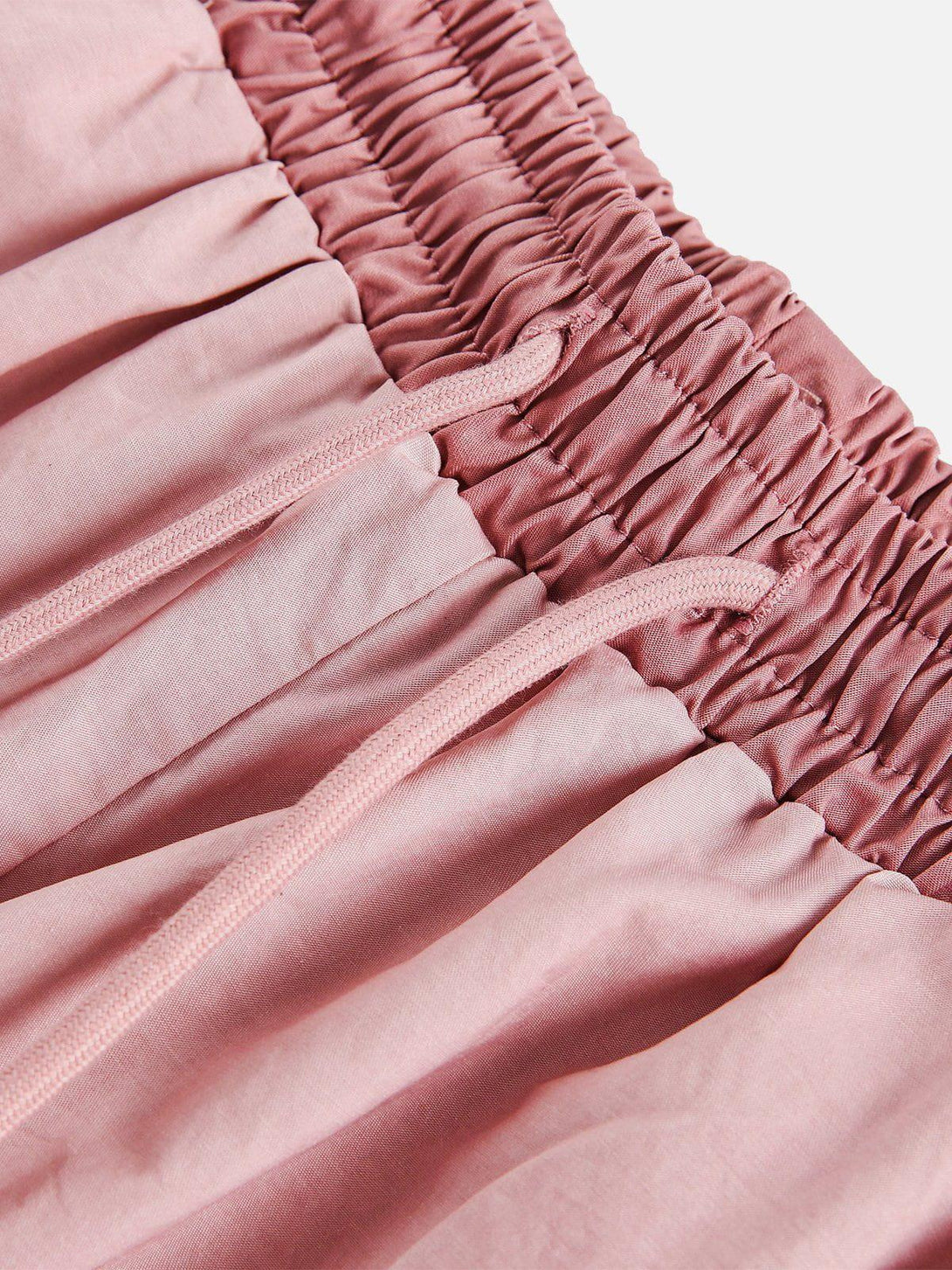 A close-up of pink drawstring shorts by TALISHKO, showcasing the intricate gathered waistband.