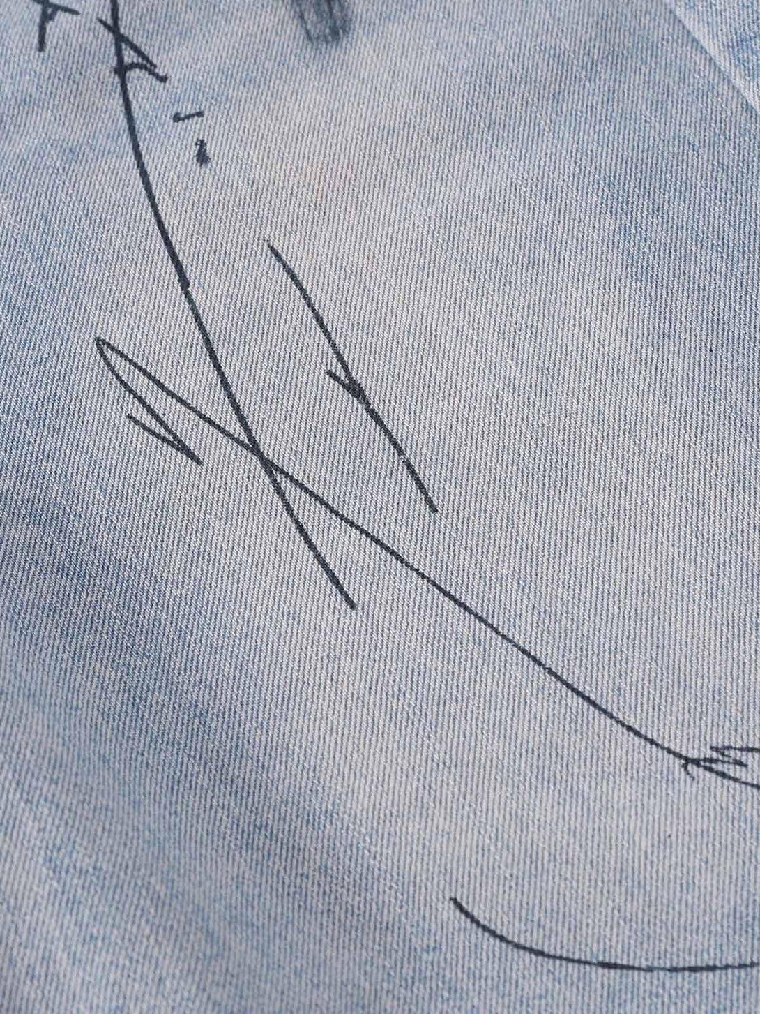 Detailed fabric and stitching of TALISHKO denim shorts, highlighting graffiti lettering design.