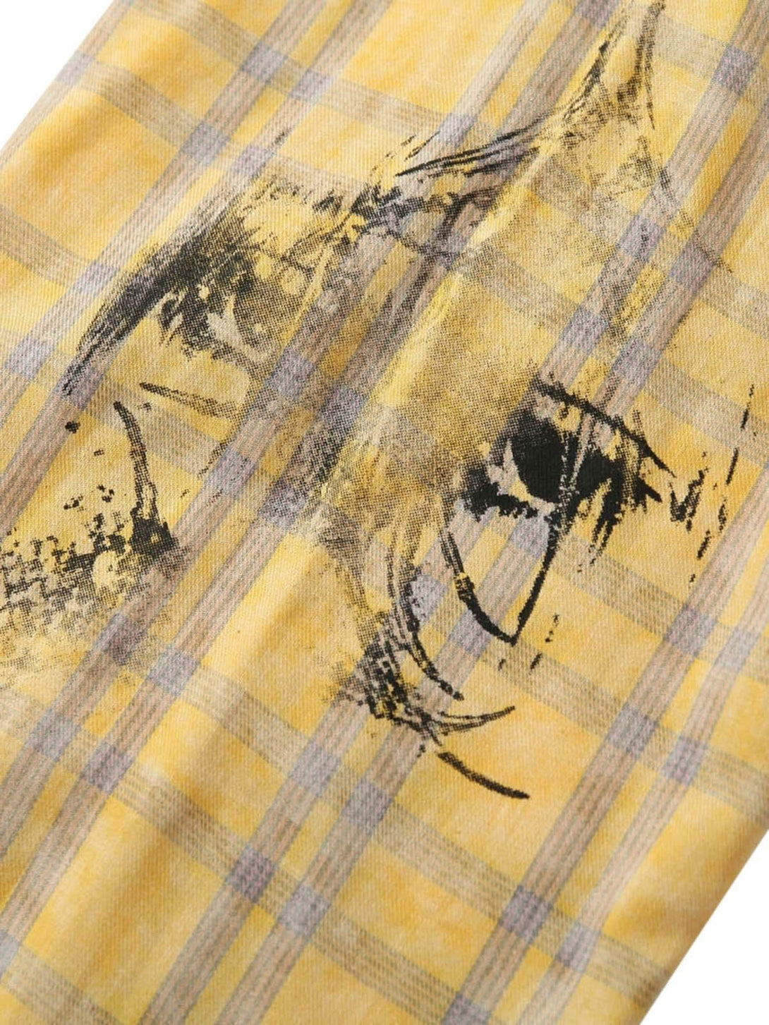 Zoomed-in texture of a yellow plaid shirt by TALISHKO, featuring artistic graffiti detailing.