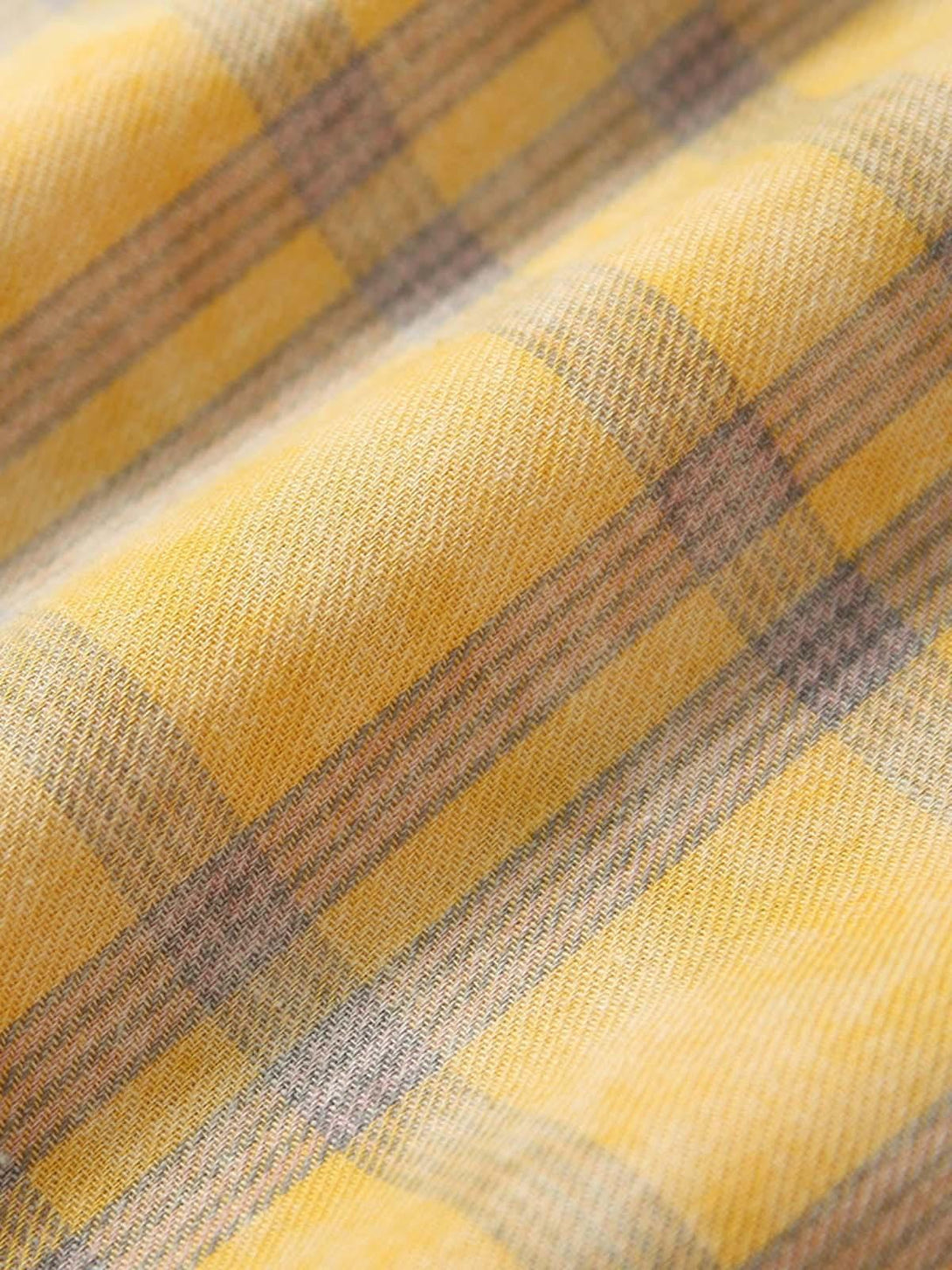 Texture and pattern showcased on TALISHKO's yellow plaid shirt, featuring intricate weave.