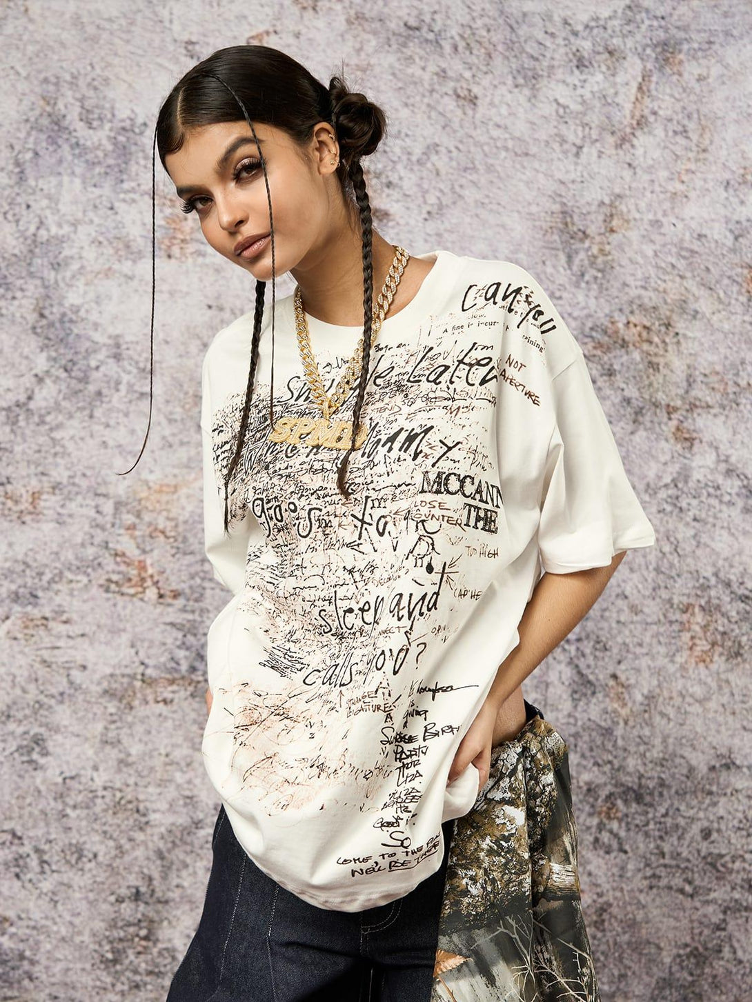 Model in TALISHKO graffiti letter print oversized T-shirt, styled with bold gold chains.