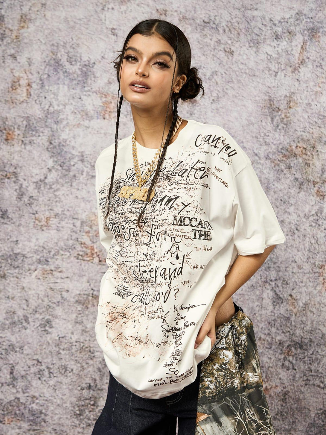 Model wearing a graffiti print oversized T-shirt by TALISHKO, styled with trendy accessories.