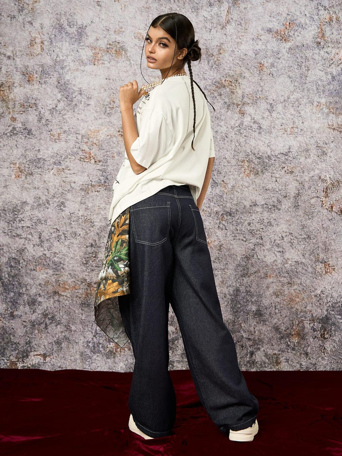 Model in TALISHKO oversized T-shirt with graffiti print, paired with wide-leg jeans.