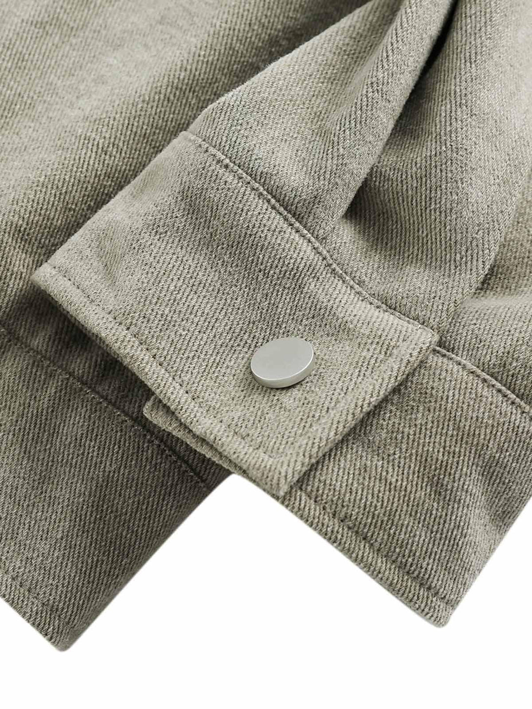 Snap detail on the cuff of a graffiti patchwork denim jacket by TALISHKO, showcasing texture.