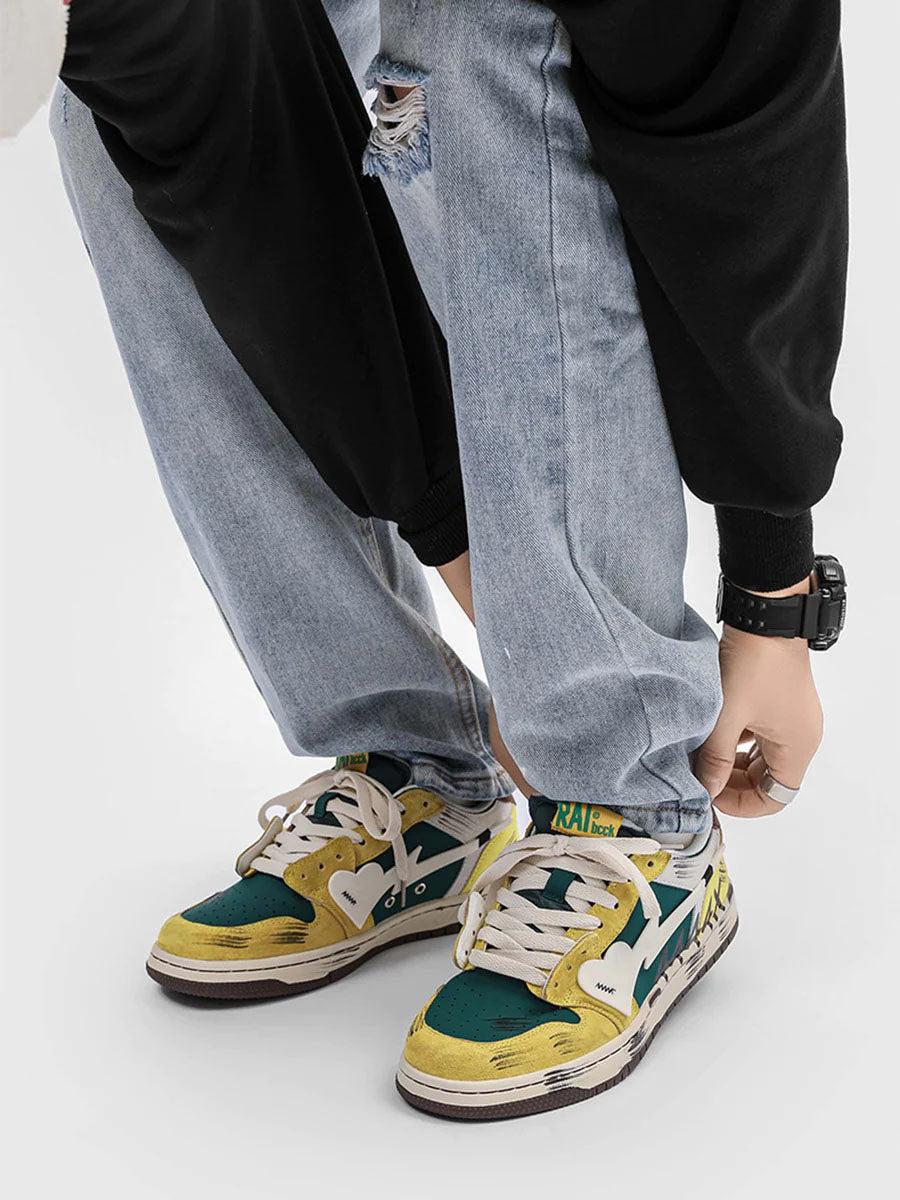 TALISHKO graffiti skate shoes in vibrant yellow and green, paired with ripped jeans for a trendy look.