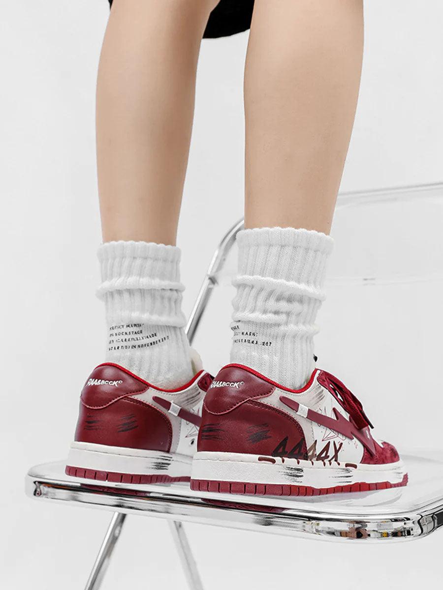 TALISHKO graffiti skate shoes in red and white, seen from the back on a clear acrylic chair.