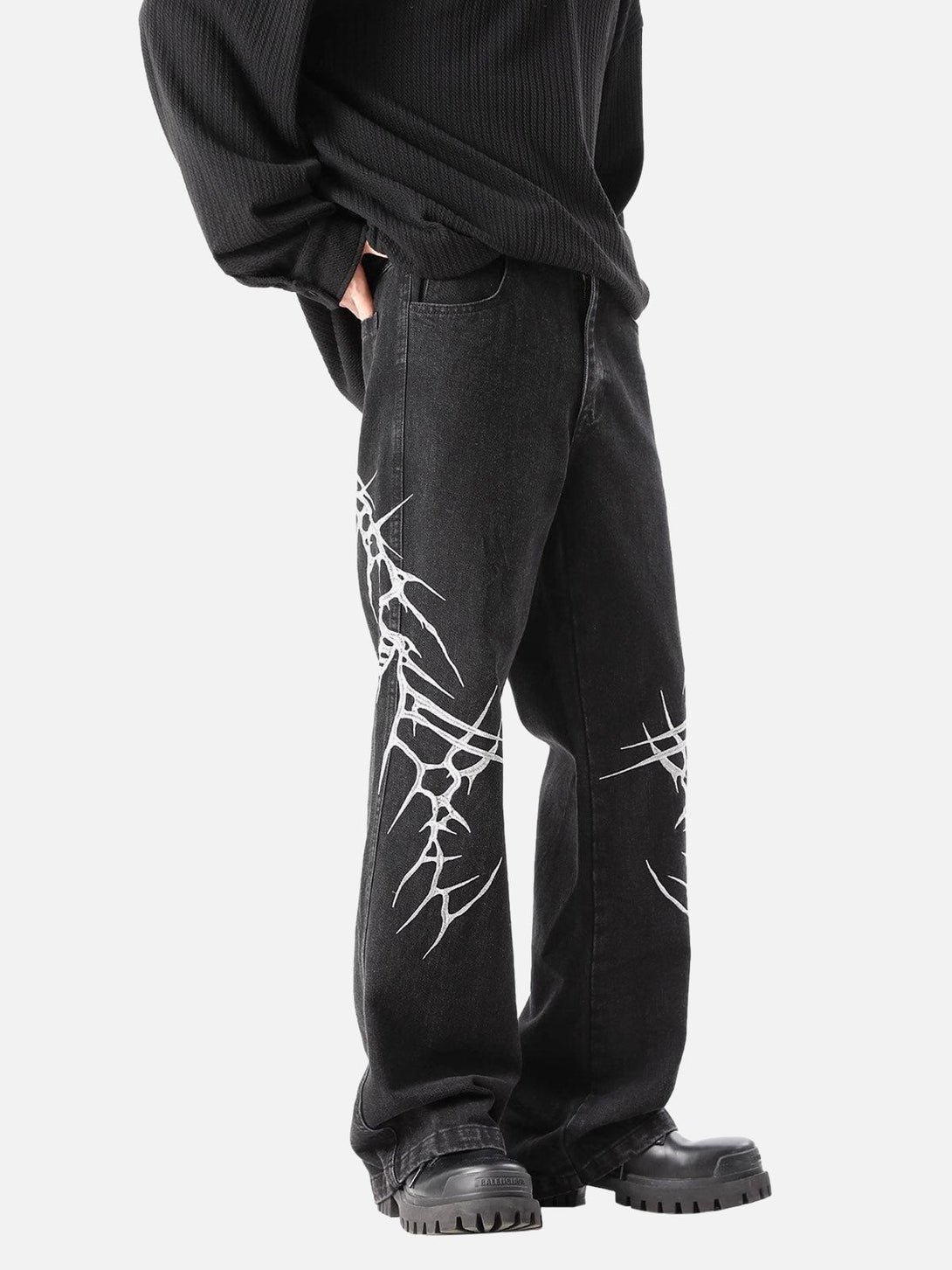 Model in TALISHKO graphic embroidered jeans, highlighting bold white designs on black denim.