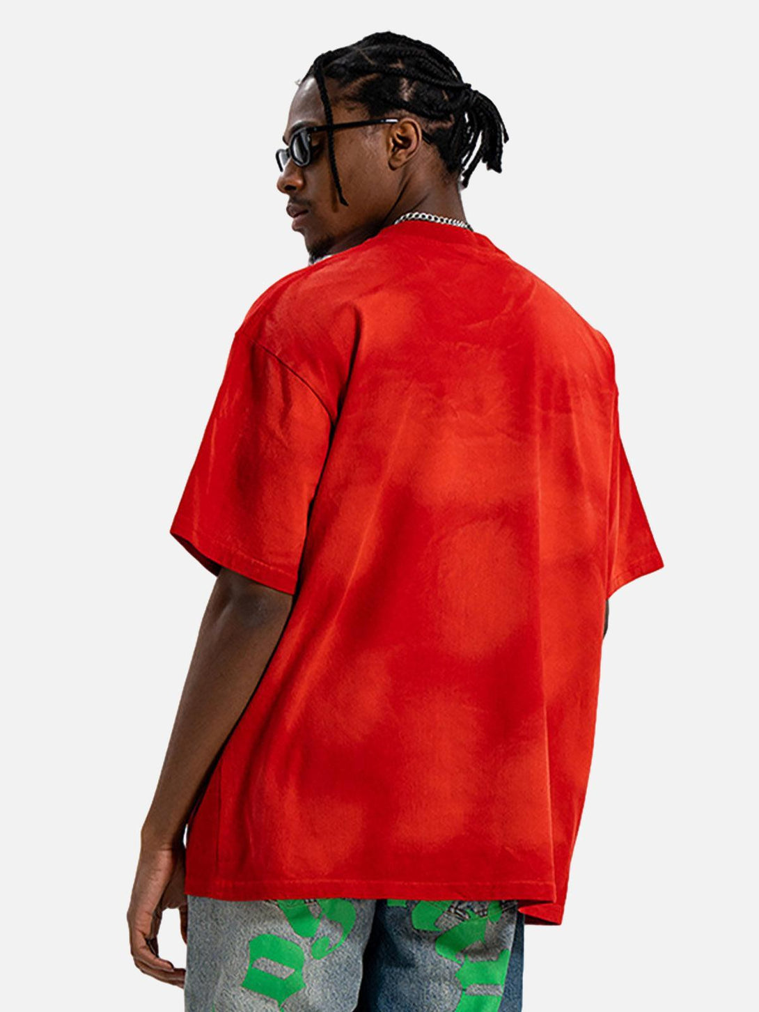 Model wearing a red graphic T-shirt by TALISHKO, showcasing a bold urban aesthetic.
