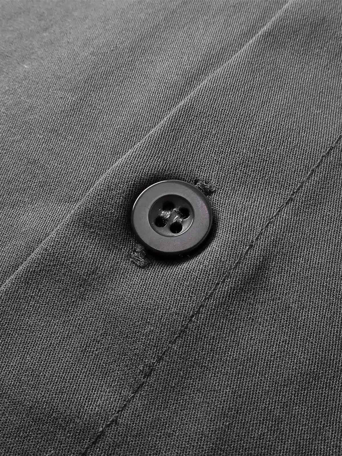 A close-up of TALISHKO shirt button, highlighting the dark fabric and stitching detail.