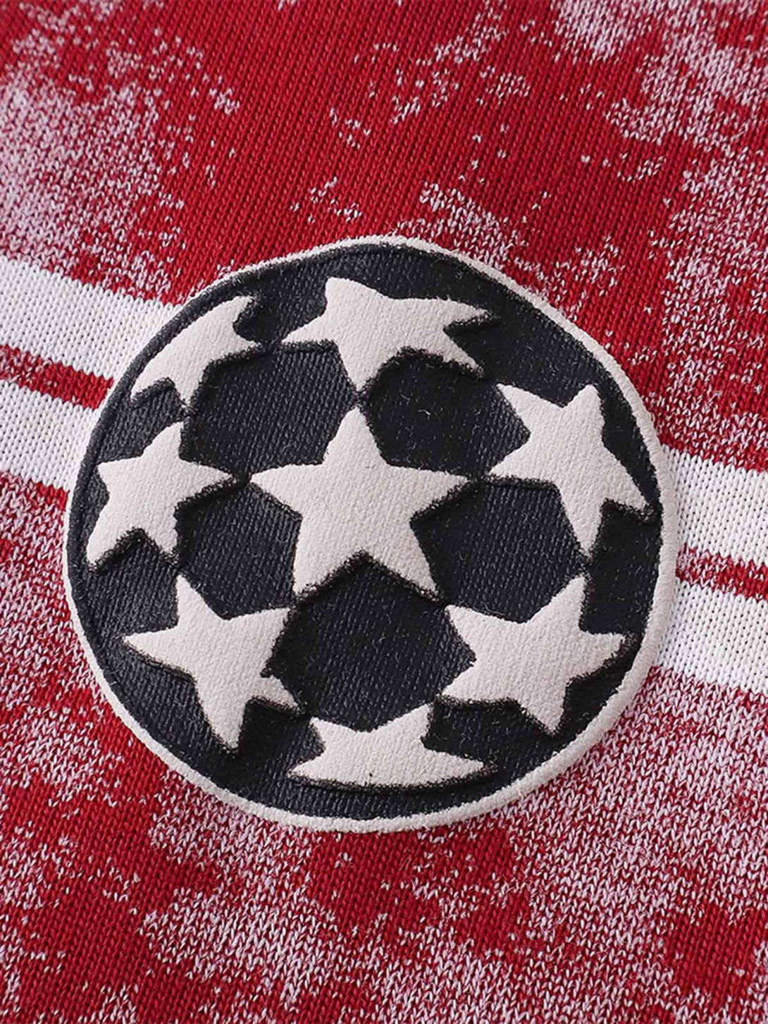 Intricate look at the star pattern patch on TALISHKO's red striped oversized T-shirt.