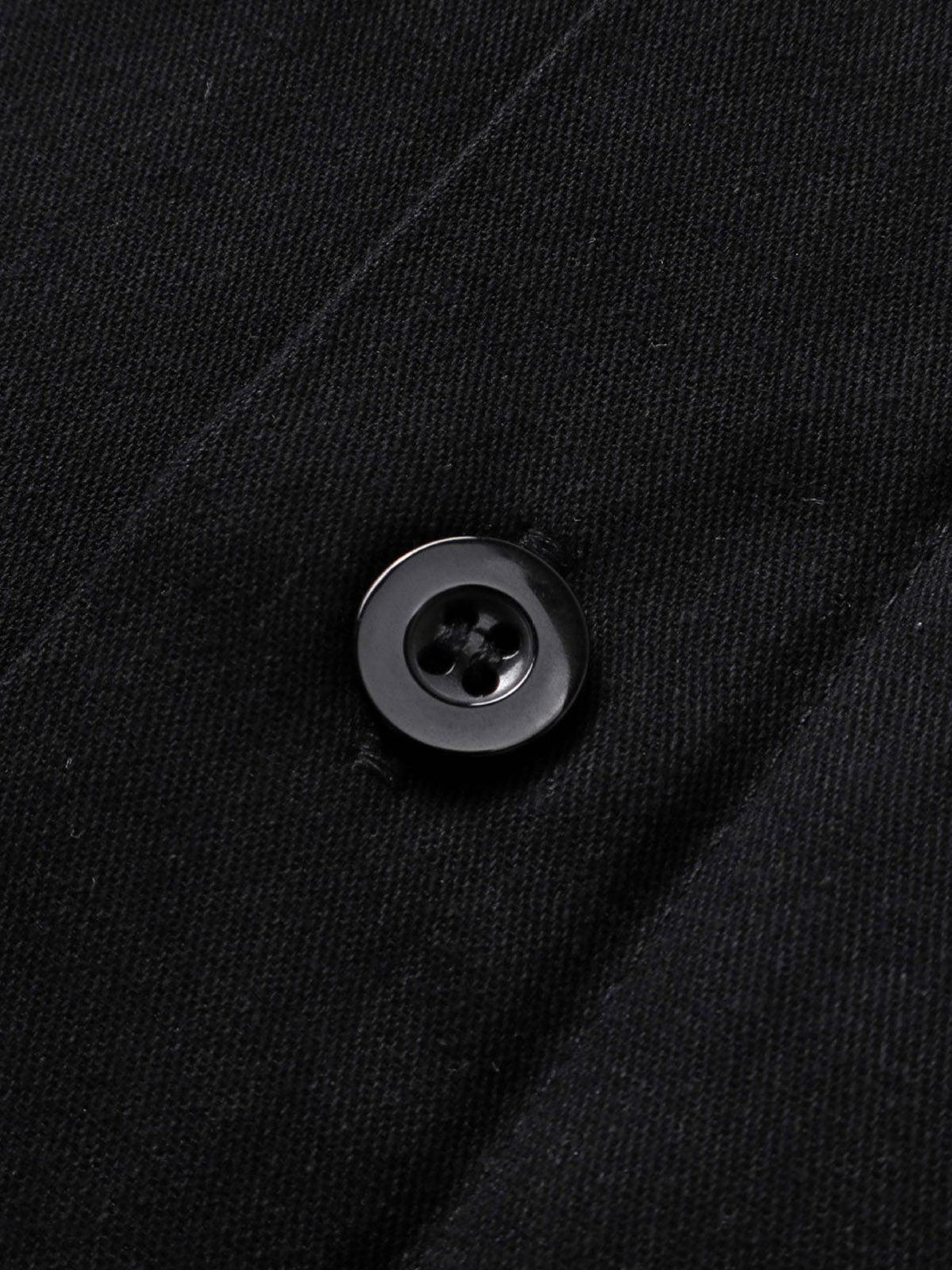 Button detail on a black long-sleeve shirt by TALISHKO, highlighting sleek fabric texture.