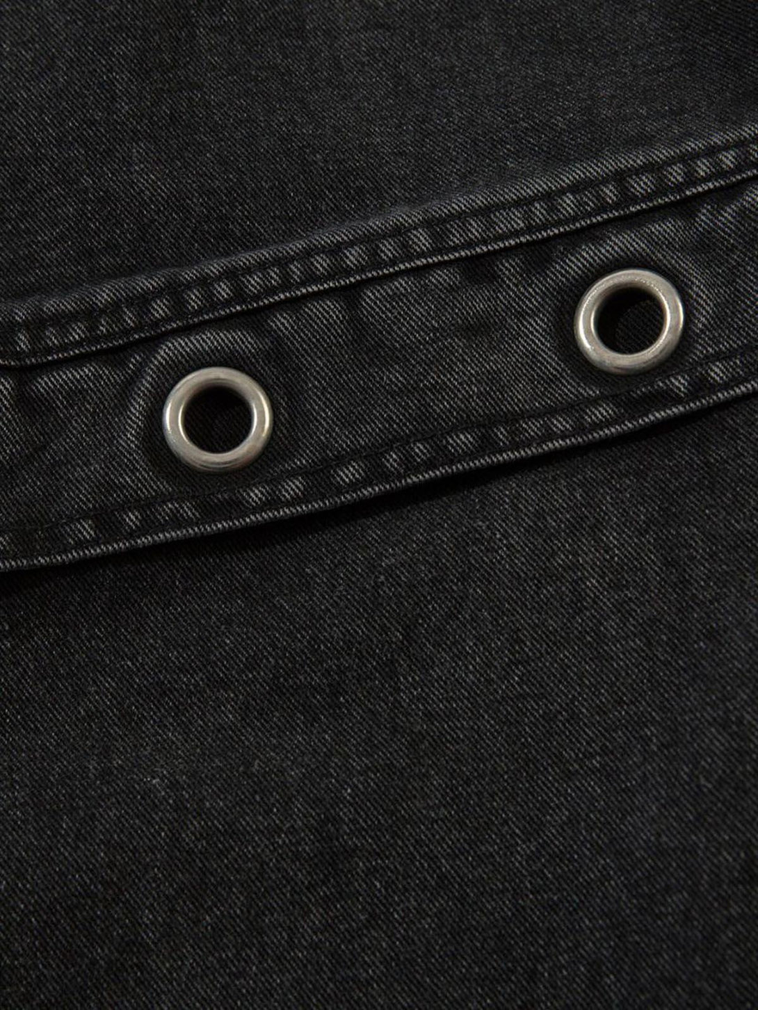 A detailed look at TALISHKO cargo jeans, featuring grommet accents on black fabric.