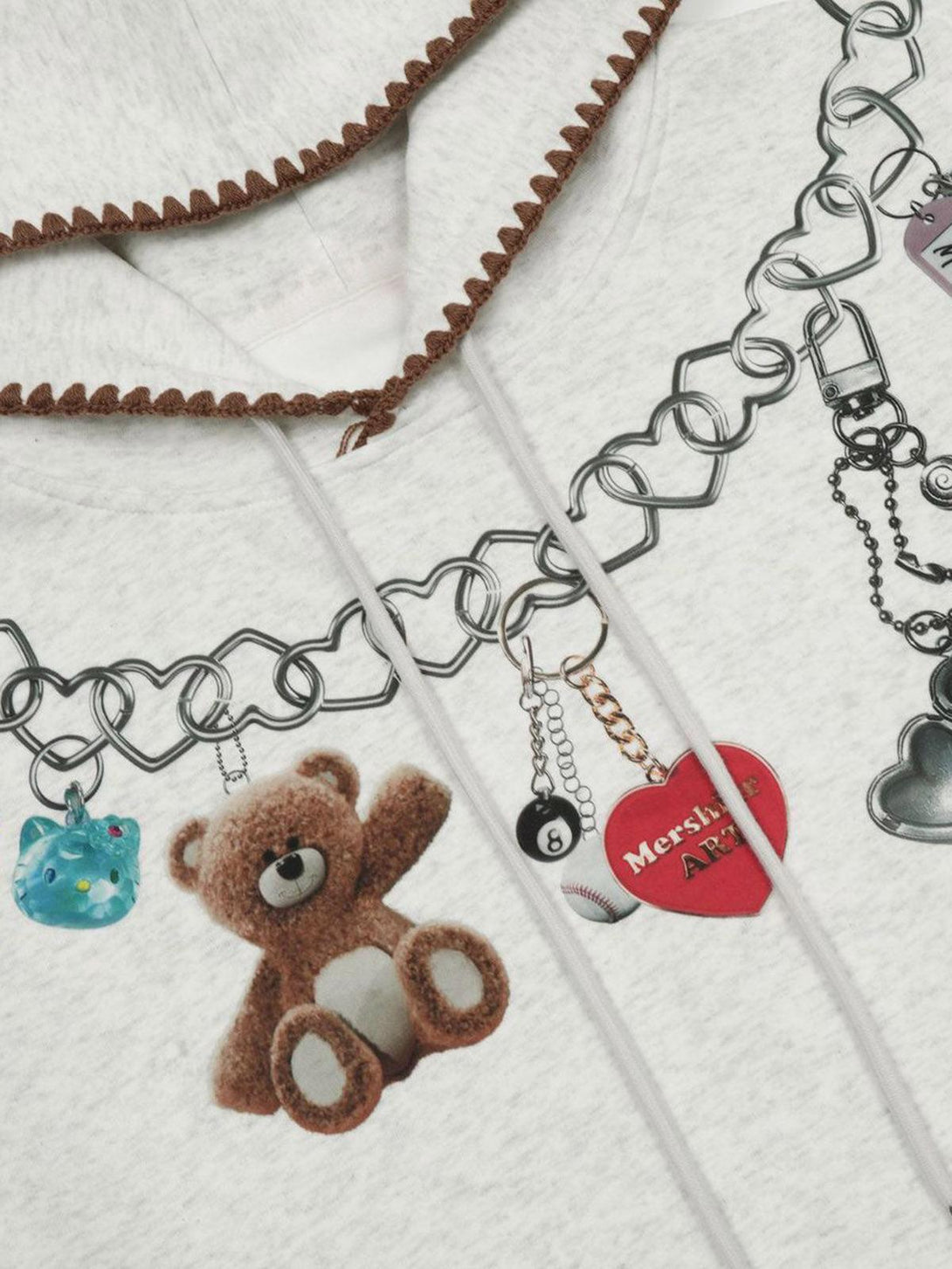 TALISHKO hoodie detail with teddy bear and heart charms on chain print, showcasing unique style.