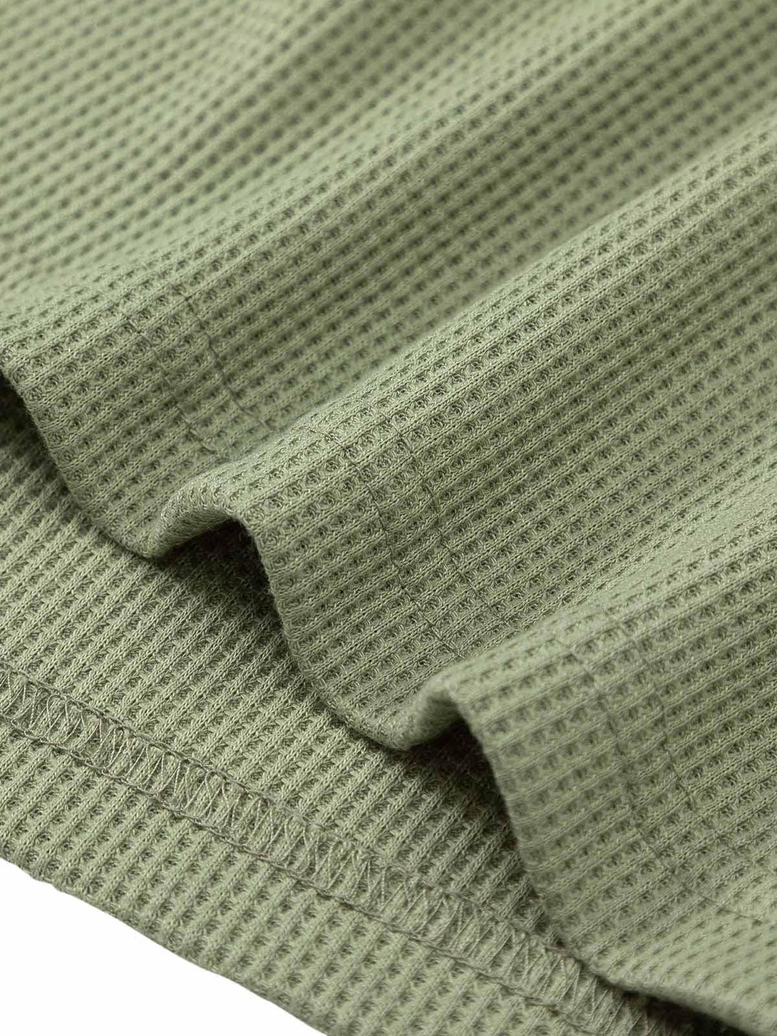 Intricate detail of TALISHKO's green knitted sweater, highlighting the textured fabric design.