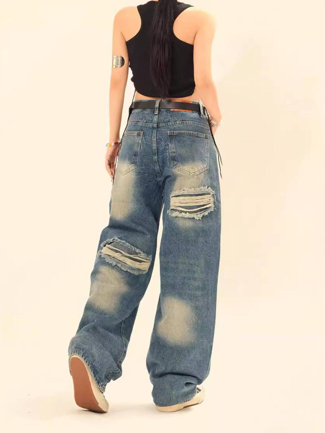 Model showcasing the back of TALISHKO ripped jeans with a relaxed fit and distressed details.